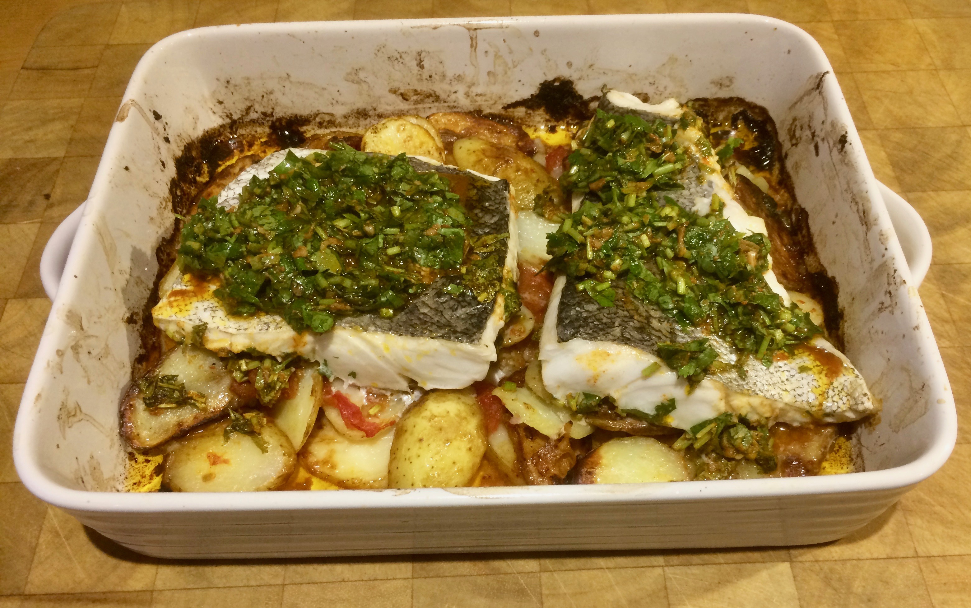 Roast hake with chermoula on a bed of new potatoes and tomatoes