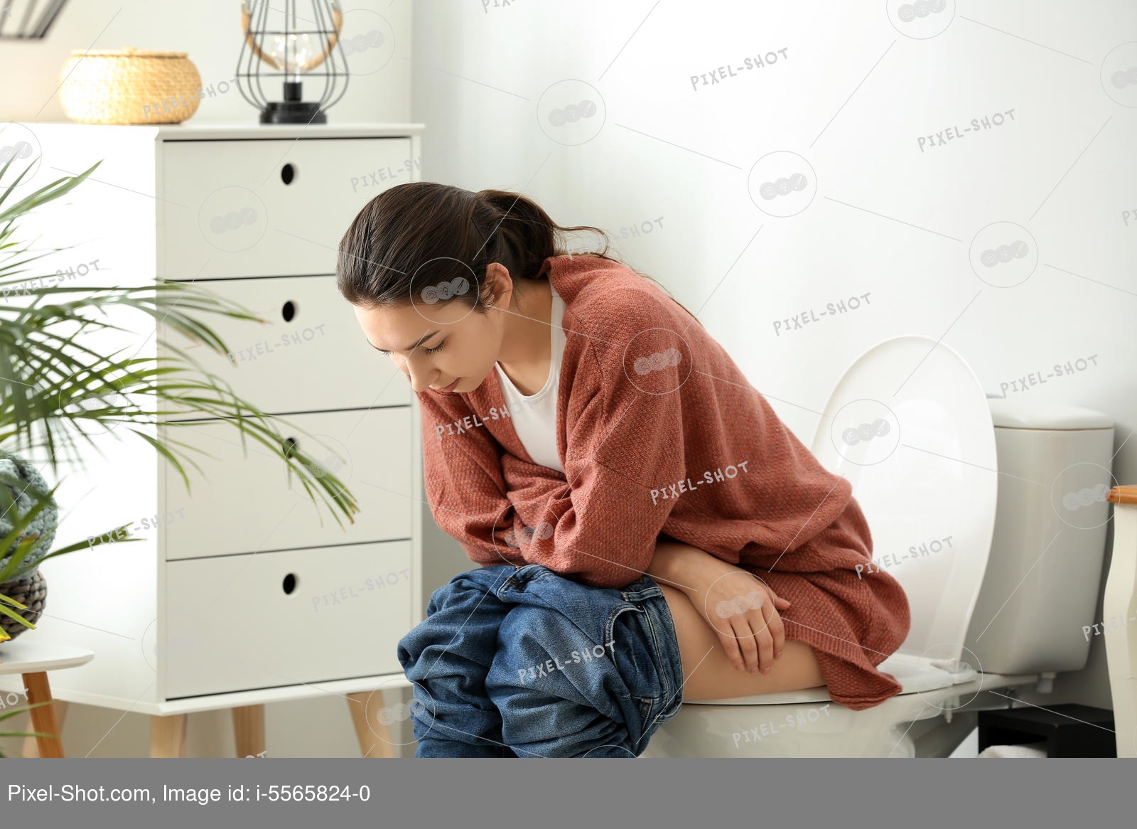 Young woman sitting on toilet bowl in restroom Stock Photography