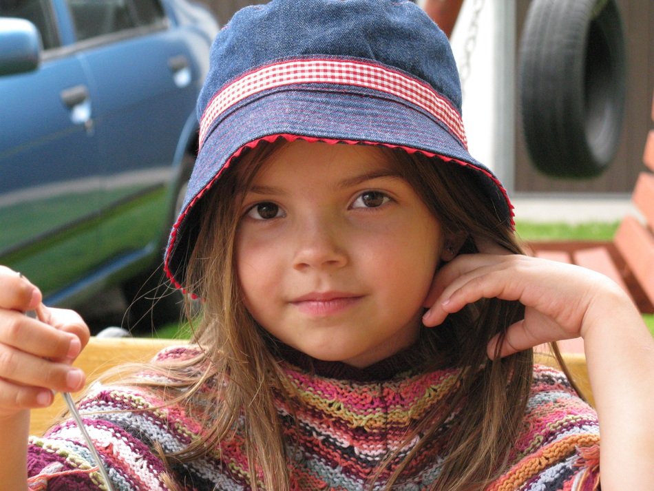 Cute child girl in blue hat looking straight free image download