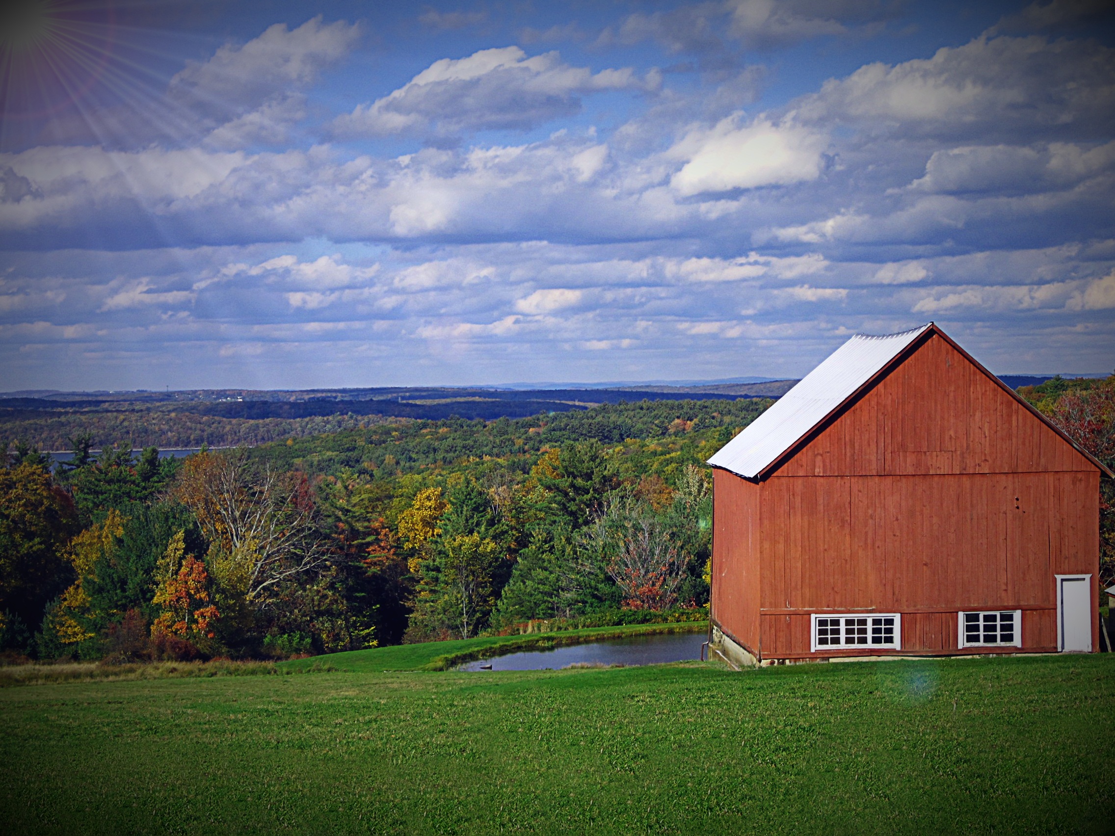Red barn on a green farm field free image download