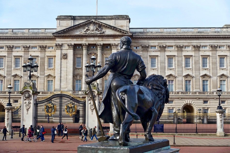 Man with hammer and lion, bronze statue at Buckingham Palace facade, uk
