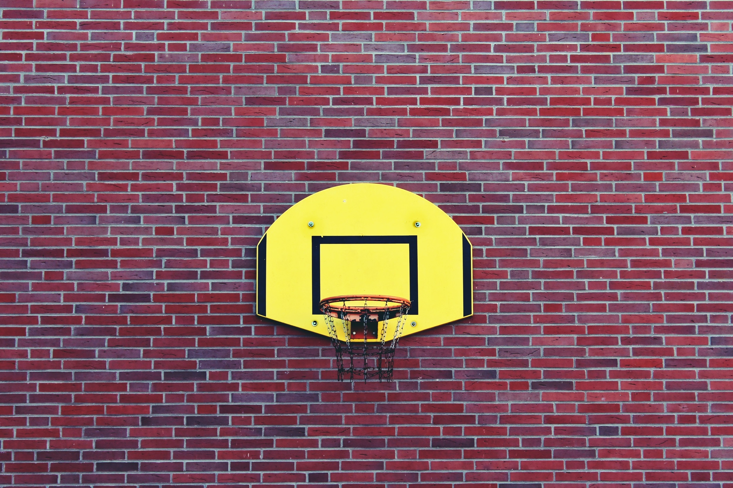 Yellow basketball backboard on red brick wall free image download
