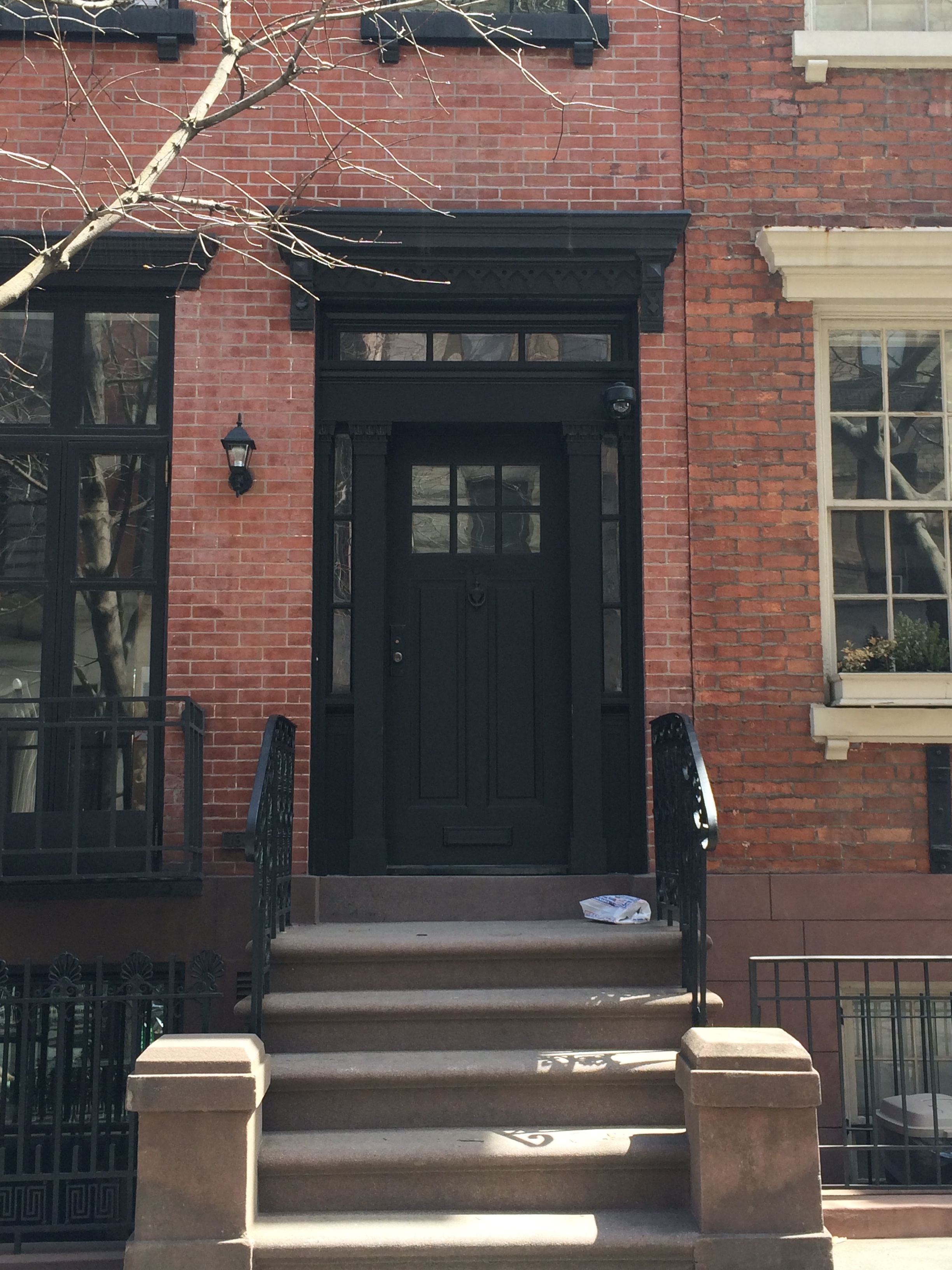 Black door in the brick house, in sunlight, in Manhattan, New York City