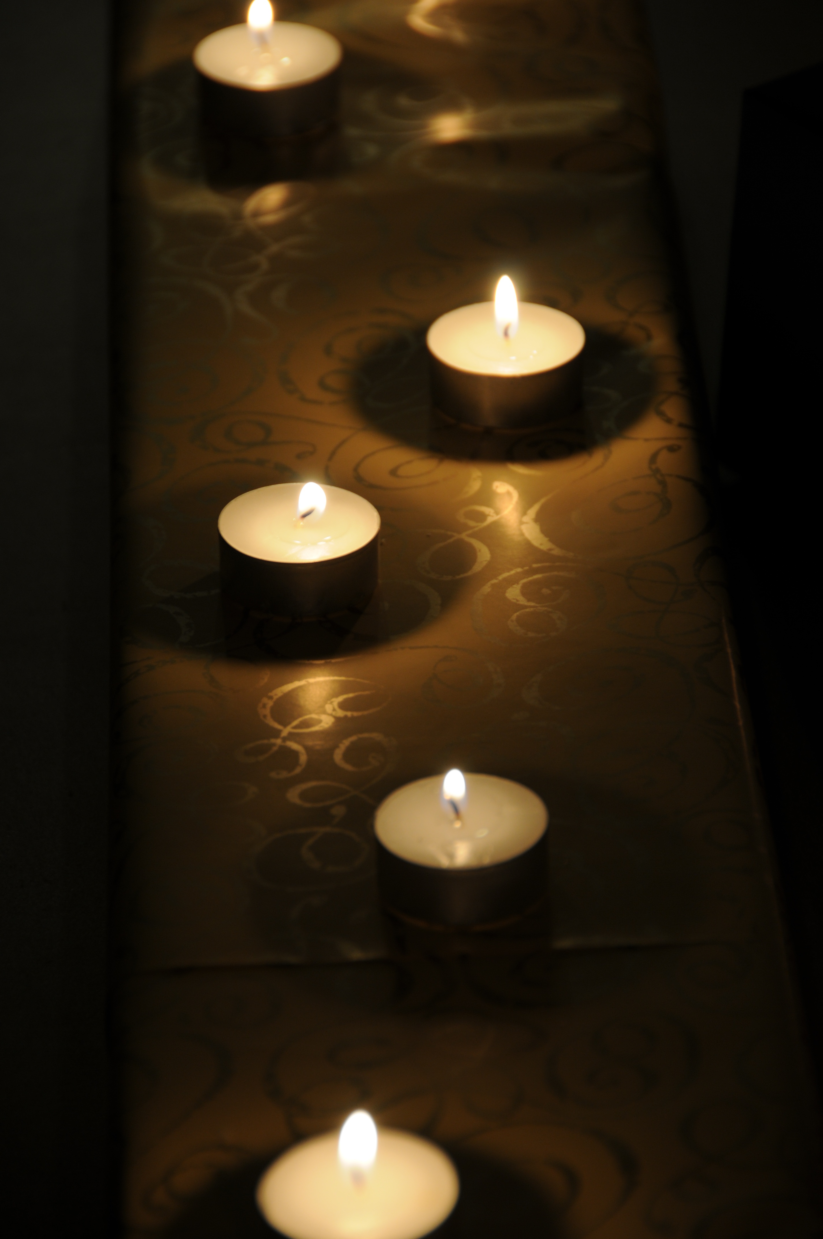 Row of five Tea Lights burning in darkness free image download