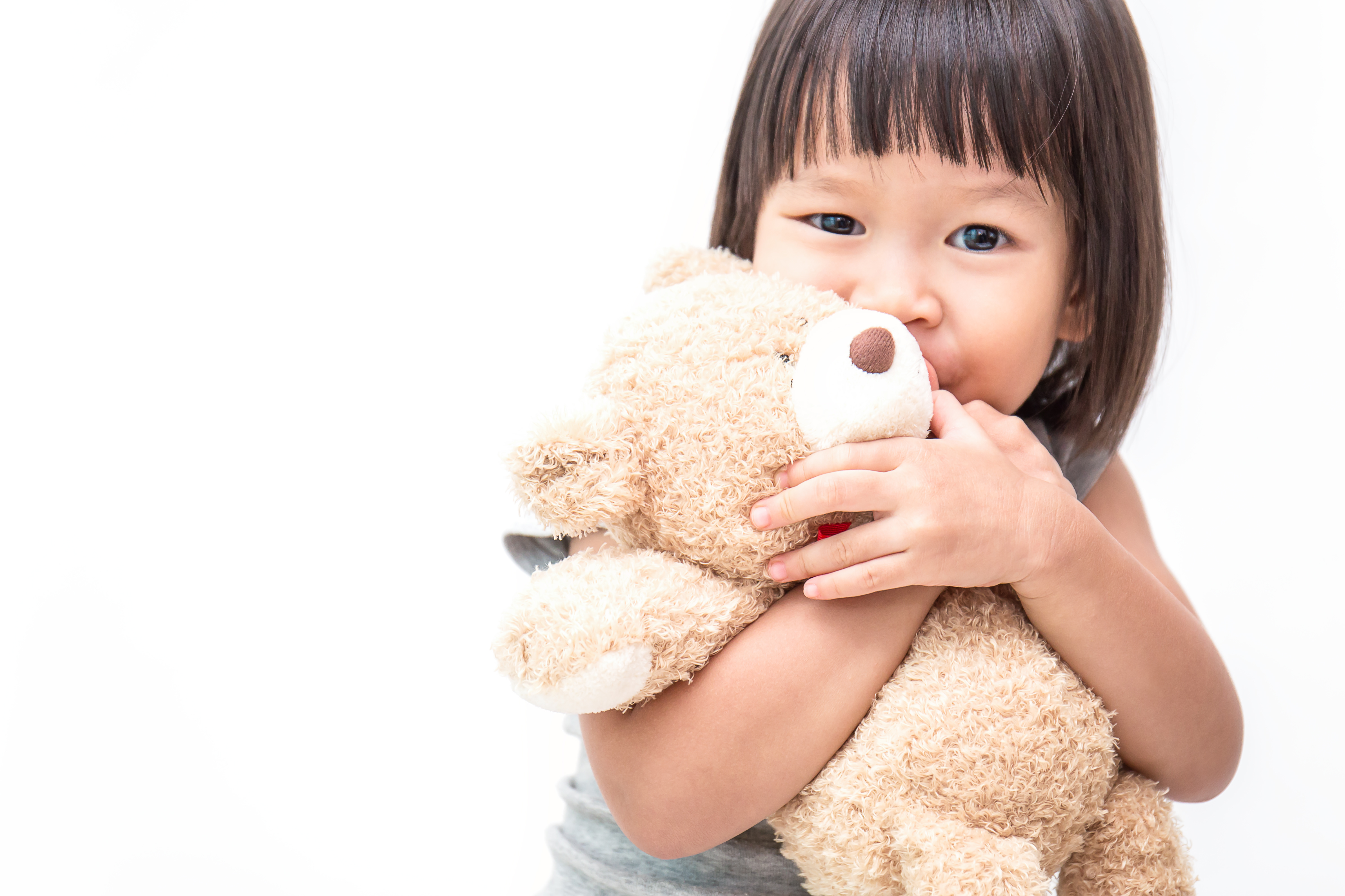 Asian cute little child girl hugging teddy bear isolated on white