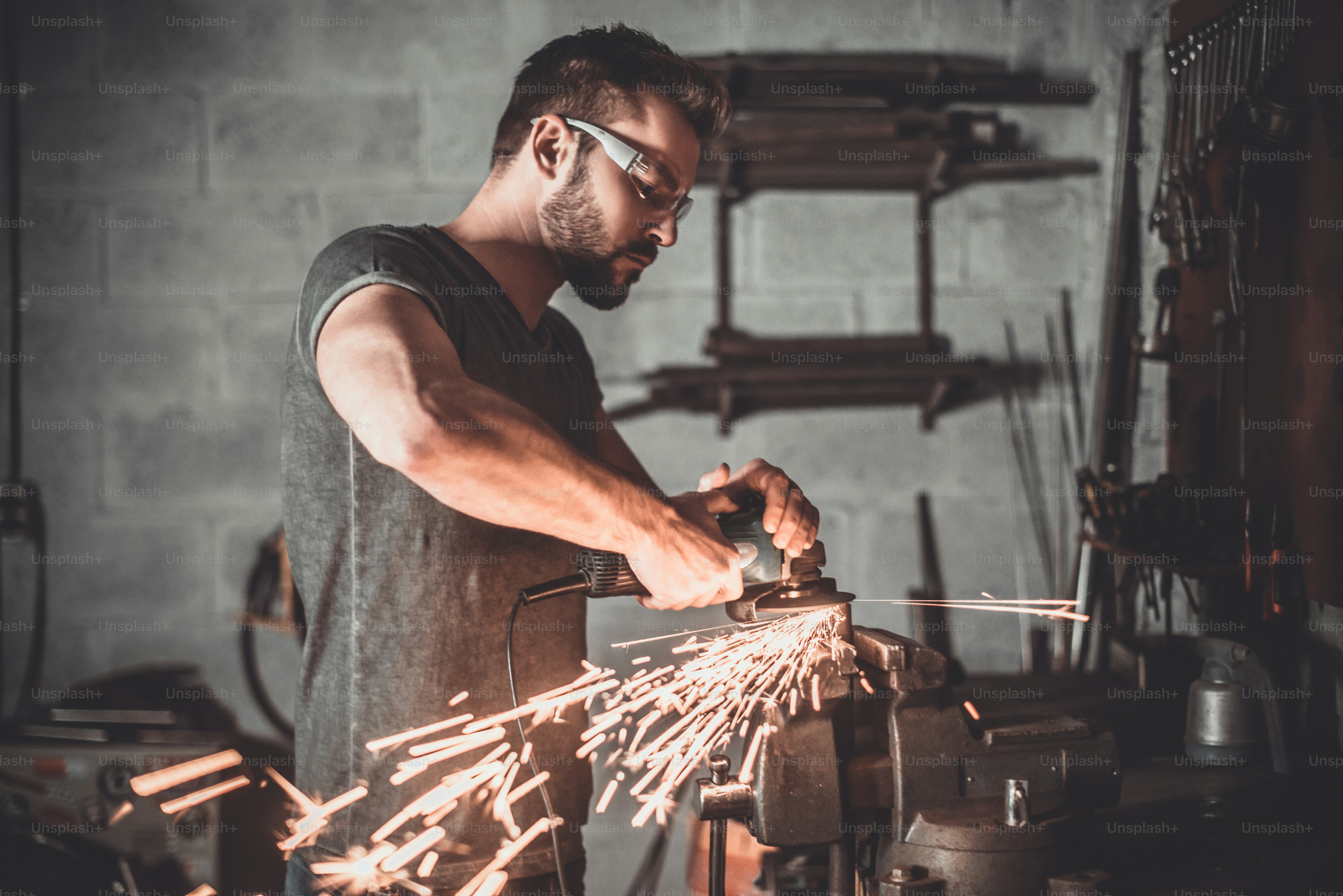 Confident young man grinding with sparks in repair shop photo Masculinity Image on Unsplash