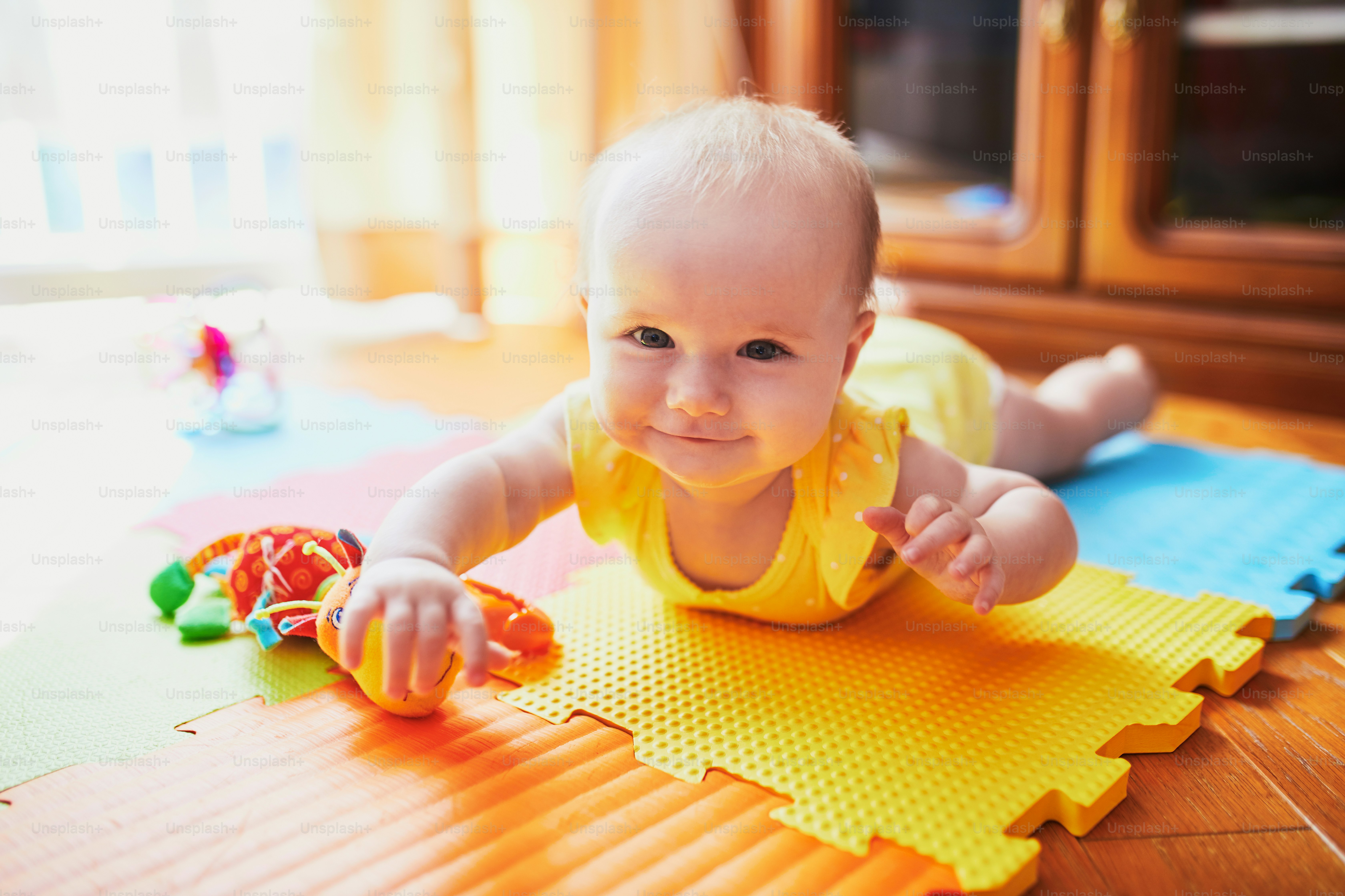Happy smiling baby girl lying on colorful play mat on the floor photo Childhood Image on Unsplash