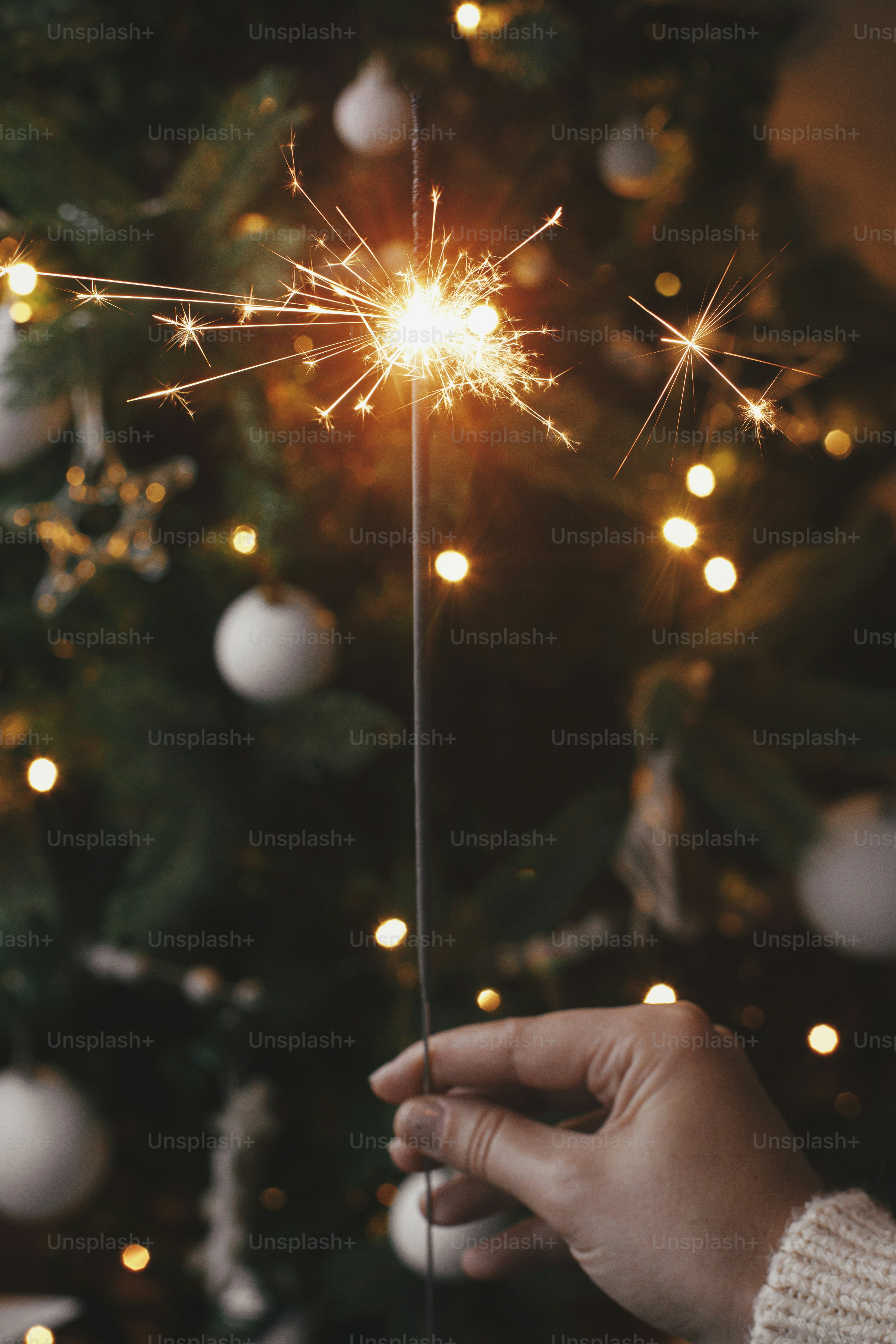 Happy New Year! Hand holding burning sparkler on background of