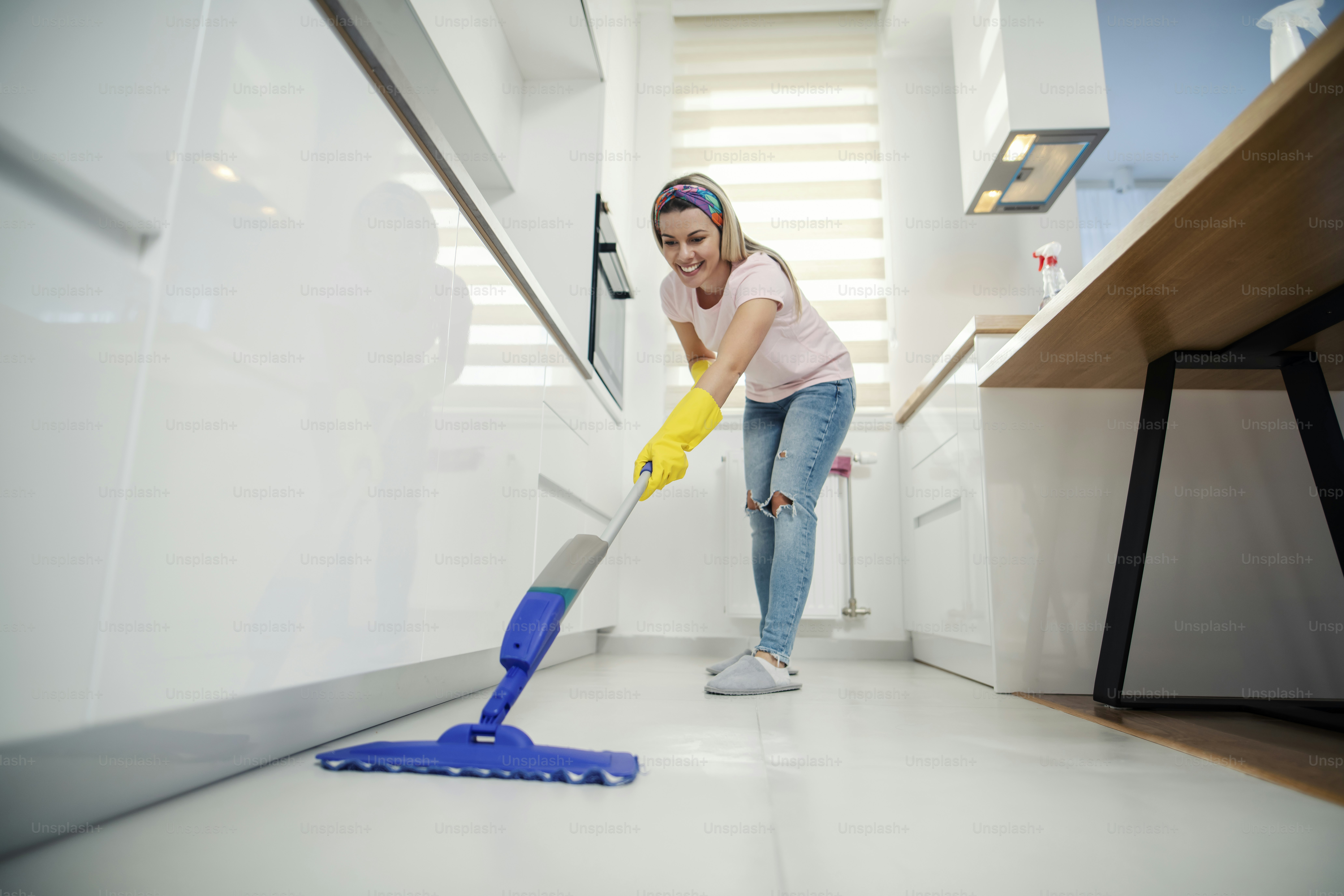 A woman doing chores, sweeping kitchen floor with mop. photo