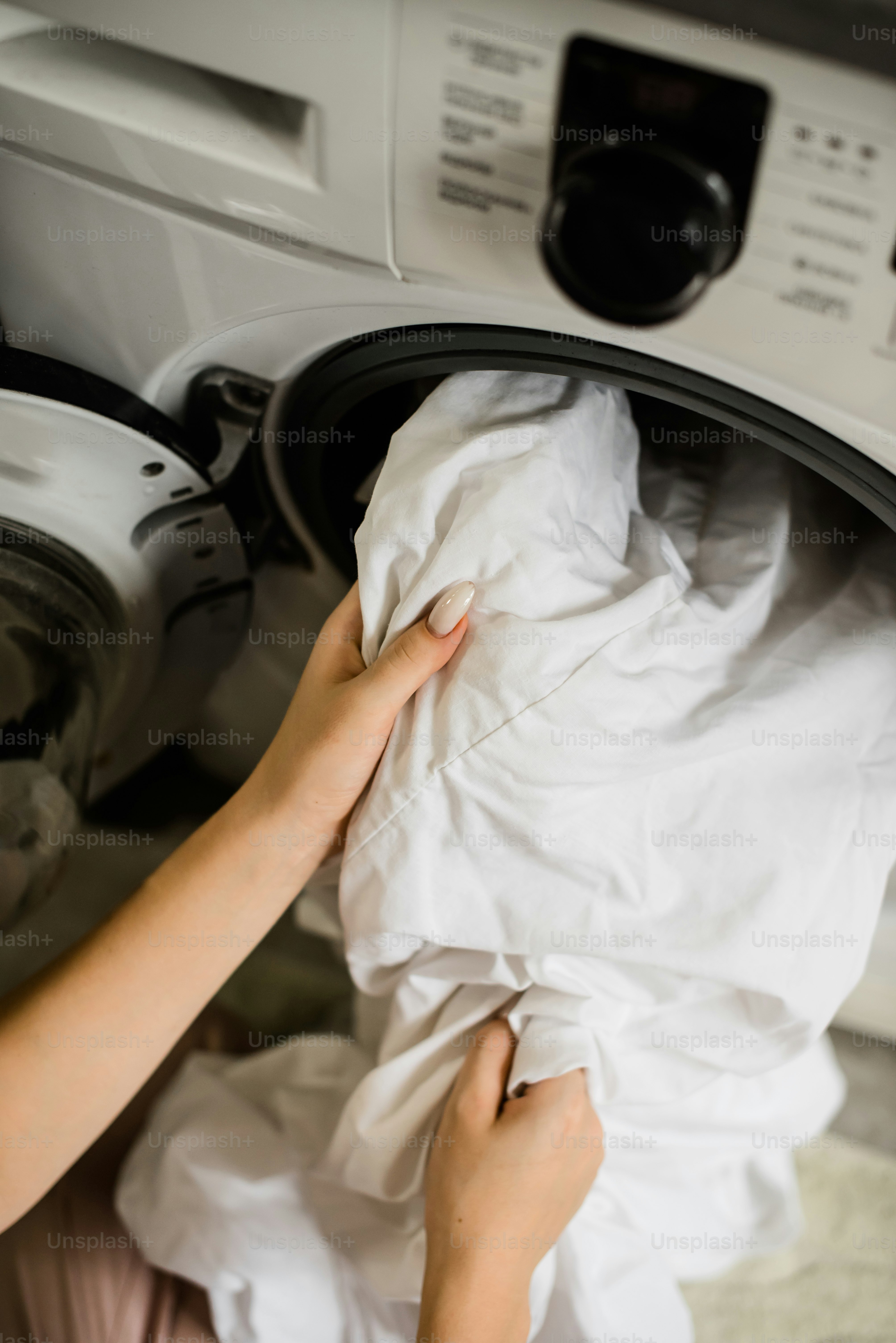 A woman is putting a cloth into a dryer photo Cleaning Image on Unsplash
