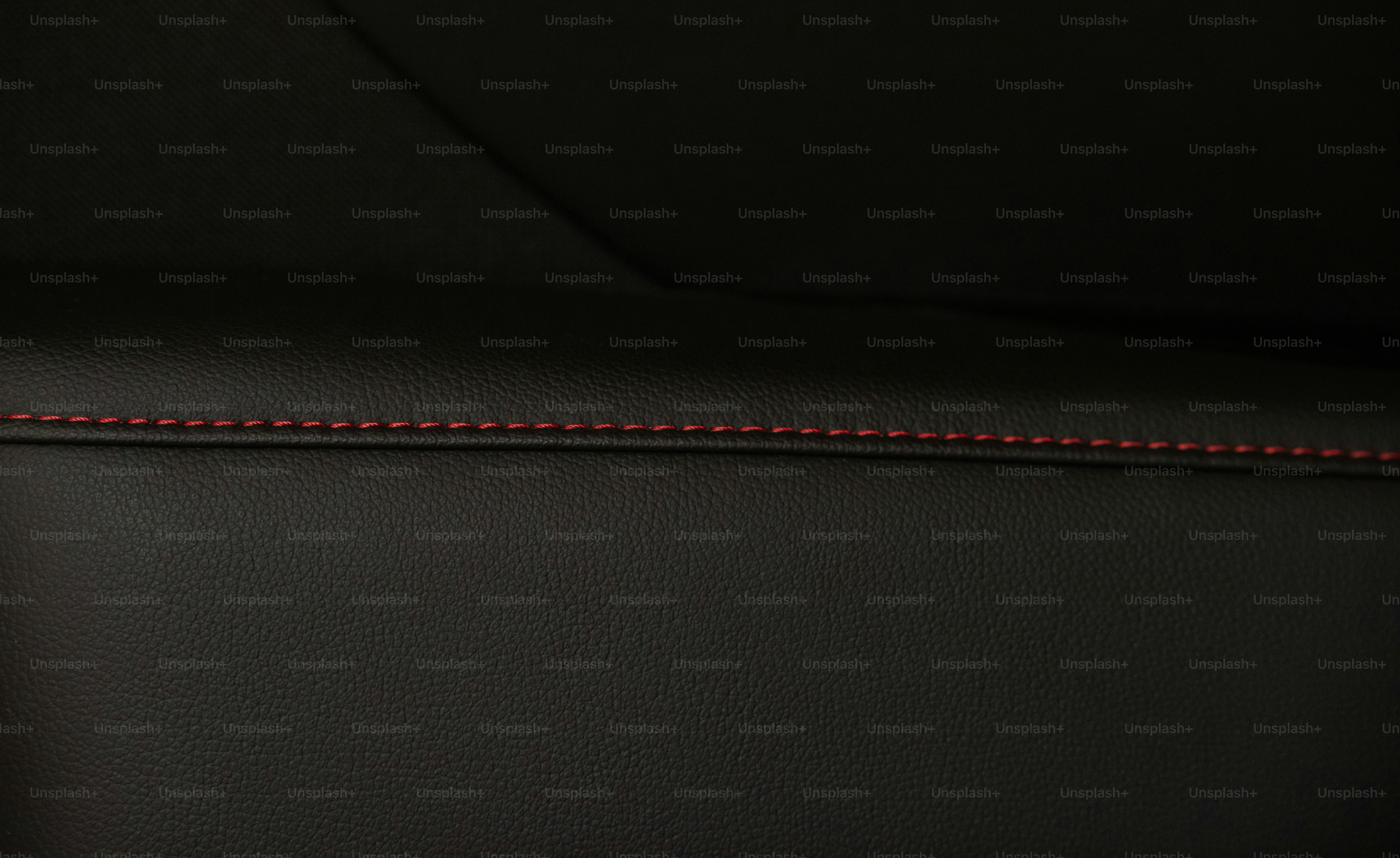 A close up of a black leather seat with red stitching photo Concept