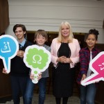 Photo of Mary Mitchell O'Connor with young students holding speech bubbles with colourful language icons