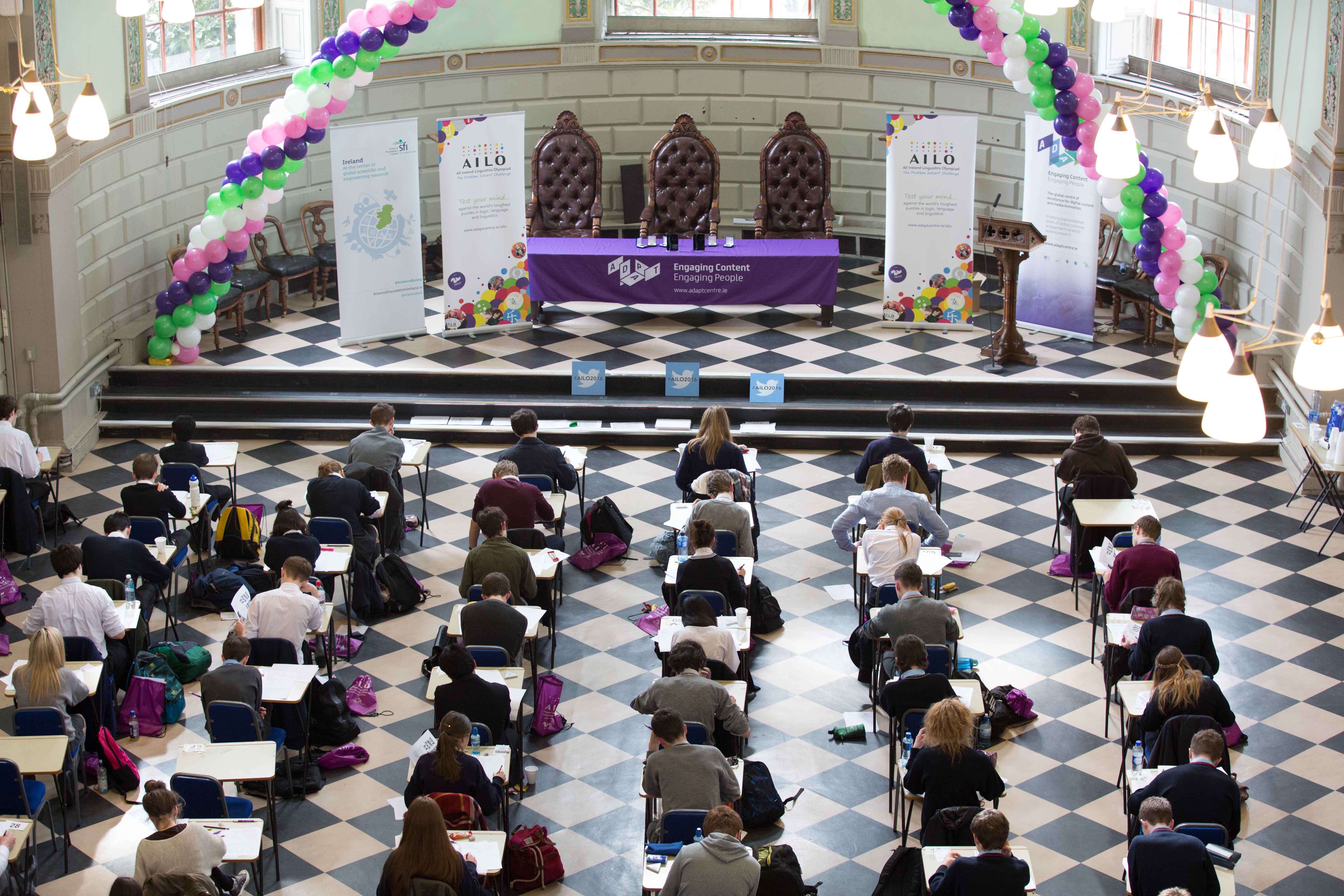 Image of students sitting in exam hall trying to solve paper-based puzzles
