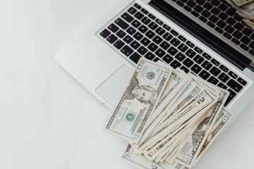 close up photo of banknotes on top of a laptop s keyboard