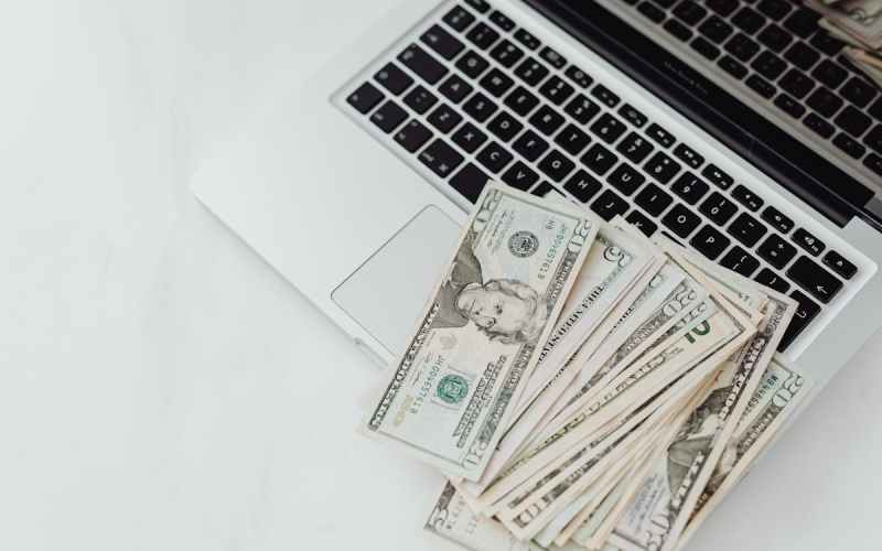 close up photo of banknotes on top of a laptop s keyboard