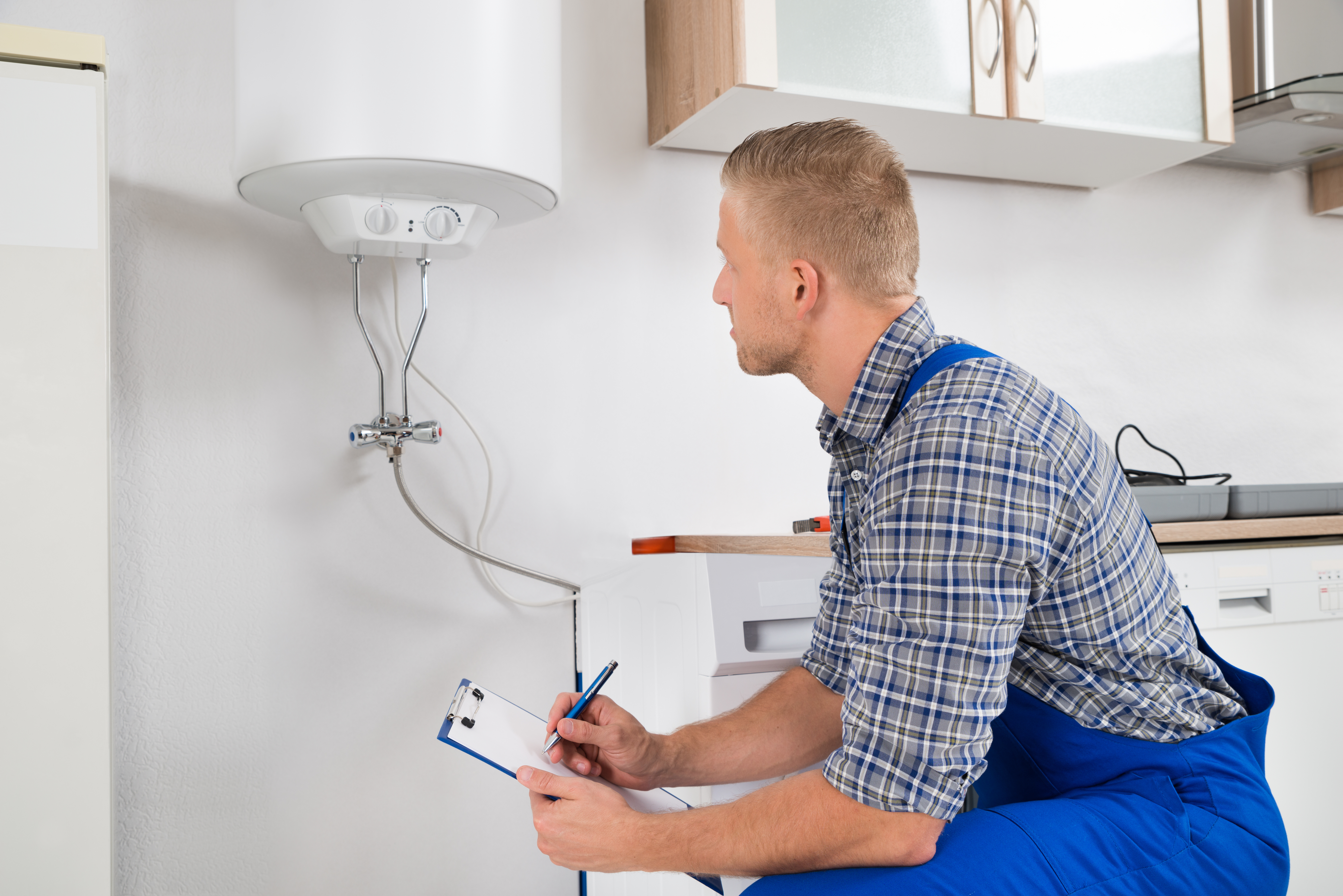 Plumber With Clipboard In Front Of Electric Boiler Proven