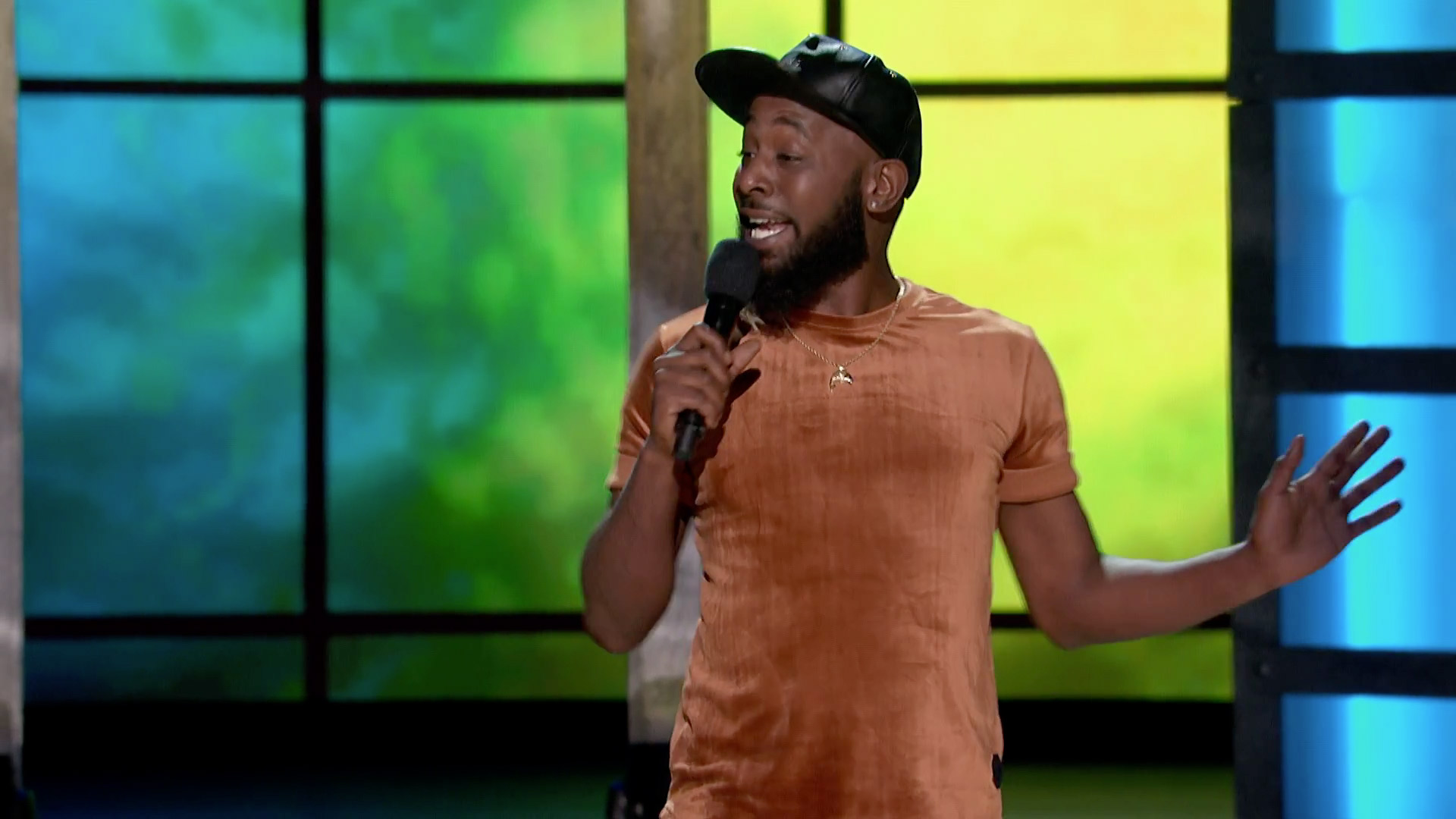 Karlous Miller wearing a velvet brown shirt and black cap while holding(023)