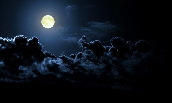 Why do clouds appear to be white or orange in the night sky on rainy