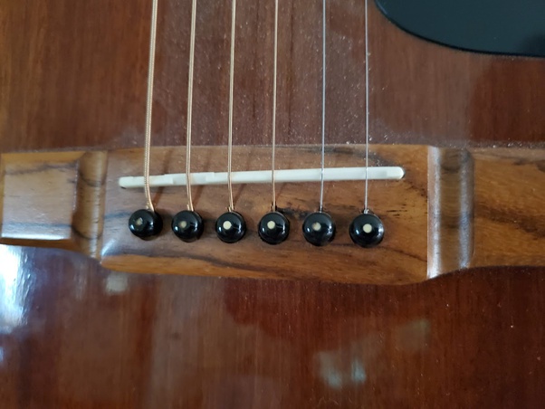 Why does the acoustic guitar bone bridge saddle have a recessed place