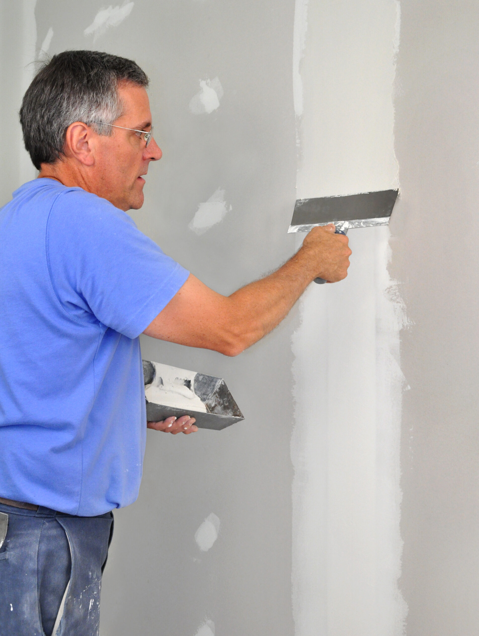 Man using trowel to finish seam between drywall panels RCA