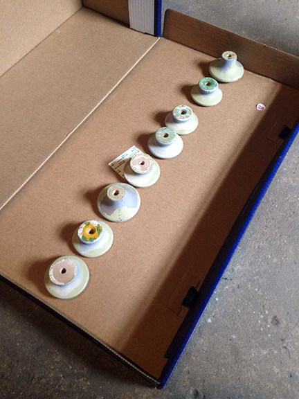 Old wooden knobs placed in a row to be spray painted.