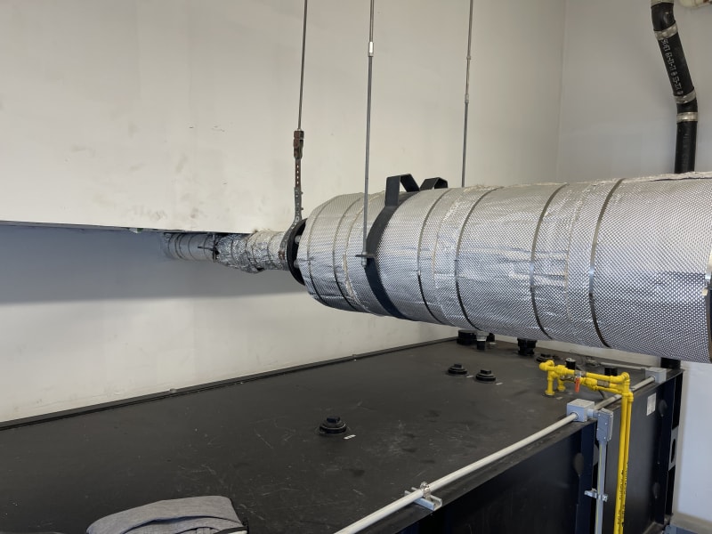 generator exhaust pipe running close to/touching concrete beam overhead