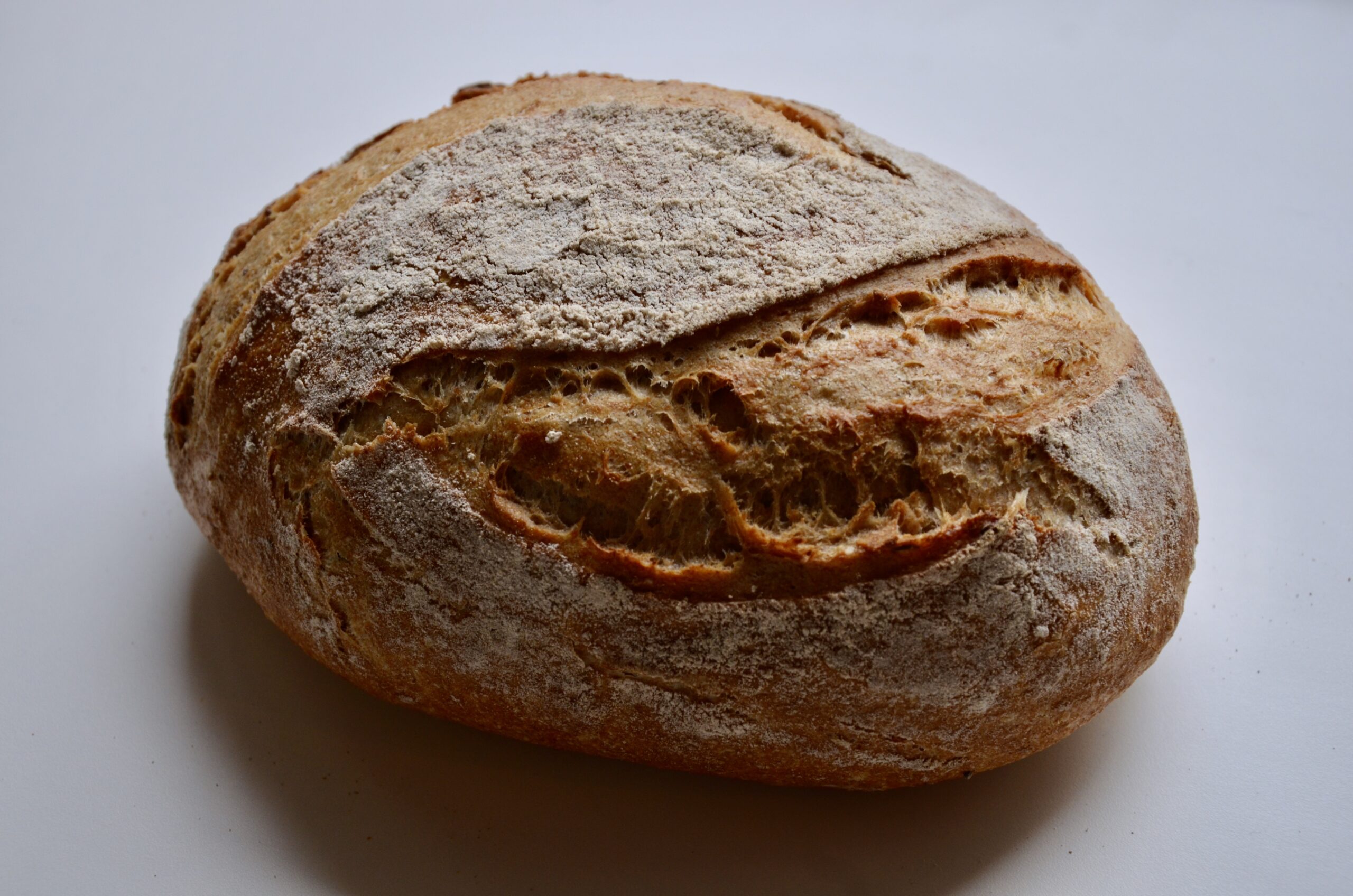 Dieses Foto zeigt das Brot von der breiten Seite. Durch Schattenwurf kommt die Kruste gut zur Geltung. Die Kruste fühlt sich spröde, knusprig, mehlig an. Wenn man mit dem Finger darüberfährt bleibt man teilweise an etwas spitzeren, knusprigen auswürfen des Teiges hängen.