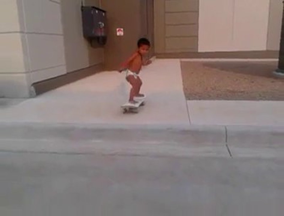 Un bébé de 2 ans en coucheculotte fait du skateboard
