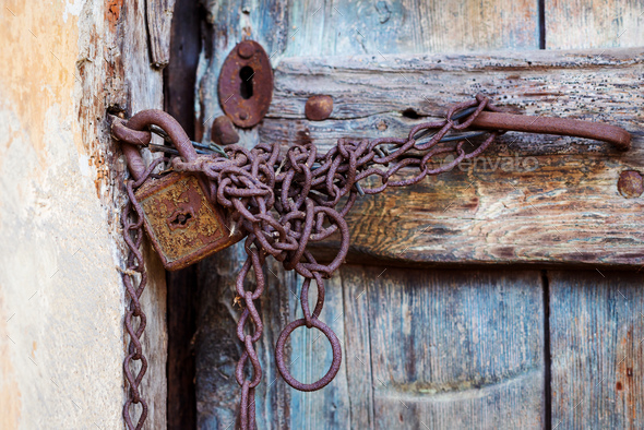 Rusty door lock and chain on an old door Stock Photo by halfpoint