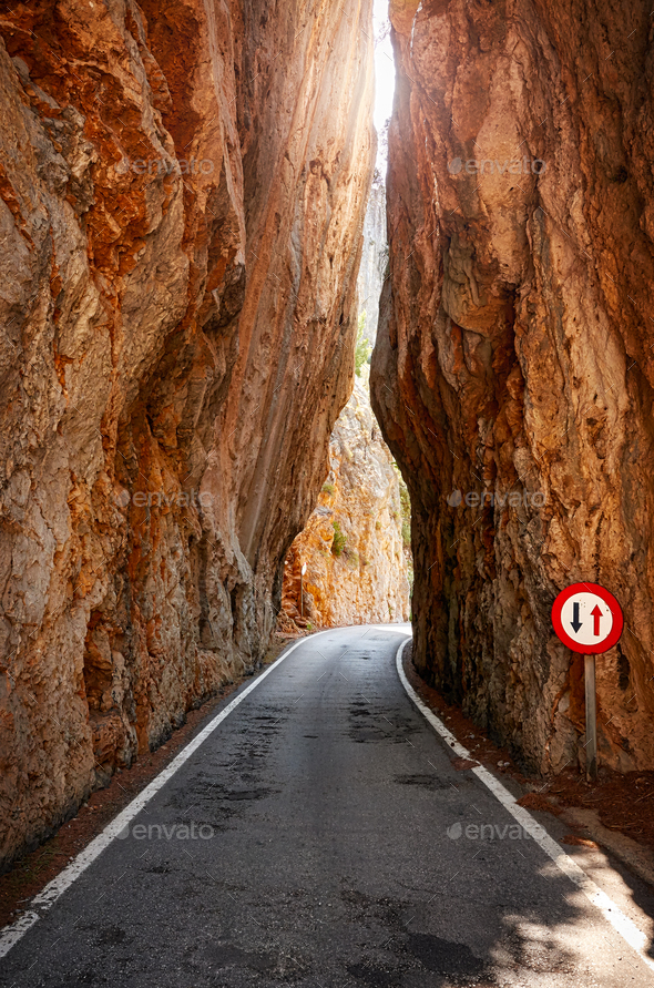 Narrow road cut through a mountain. Stock Photo by Maciejbledowski
