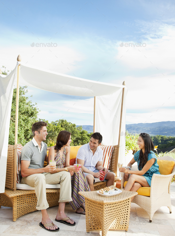 Multi ethnic couples in outdoor lounge by the pool at a luxury resort