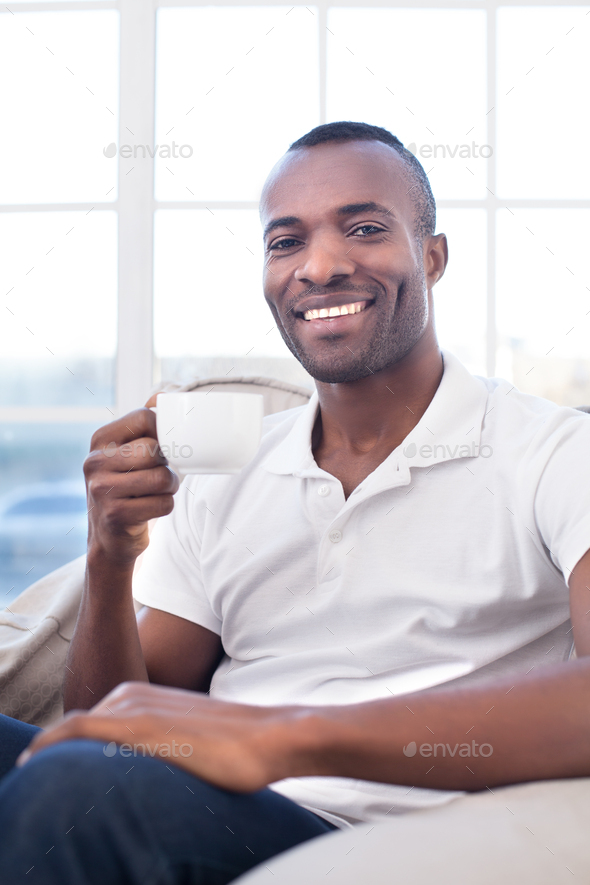 Man drinking coffee. Cheerful African man drinking coffee and smiling