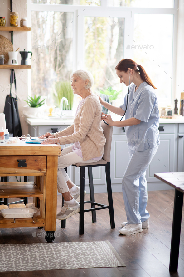 Medical attendant examining pensioner in the morning Stock Photo by