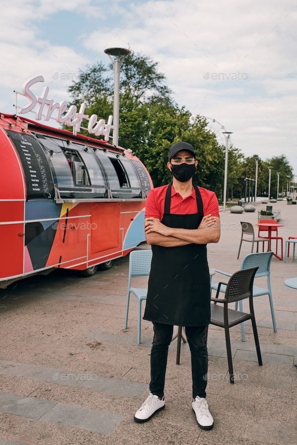 Clerk of street food truck in uniform and protective mask Stock Photo