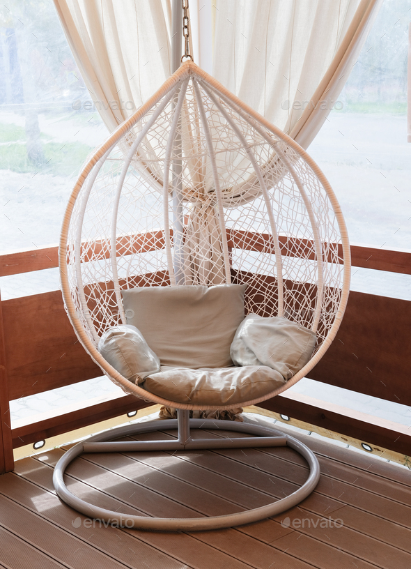 Wicker rattan hanging chair nest on a terrace Stock Photo by Yulia_Panova