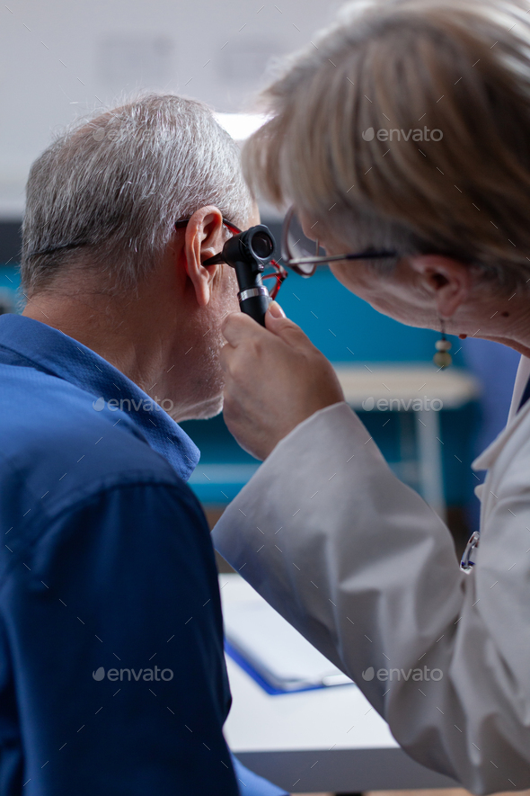 Close up of medic using otoscope to do ear examination for aged patient