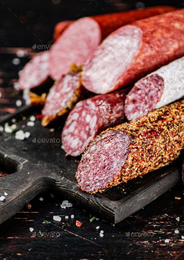 Different types of salami sausage on a cutting board. Stock Photo by