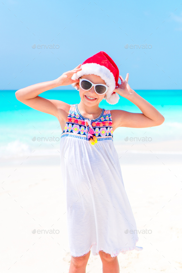 Adorable little girl in Santa hat during Christmas beach vacation Stock