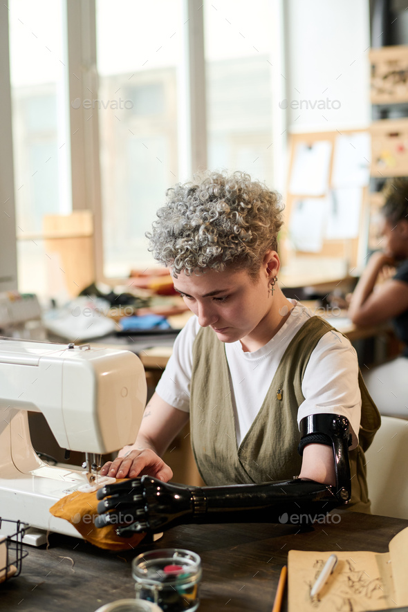 Contemporary young woman with disability working by electric sewing
