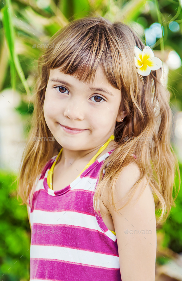 girl with a plumeria flower in her hair against the backdrop of palm trees. Selective focus