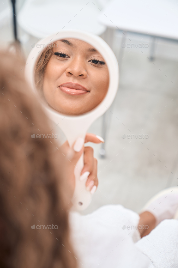 Reflection of a beautiful female face in the mirror Stock Photo by Iakobchuk