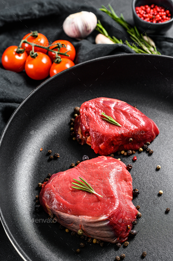 Filet Mignon steak in a frying pan. Beef tenderloin. Black background. Top view Stock Photo by