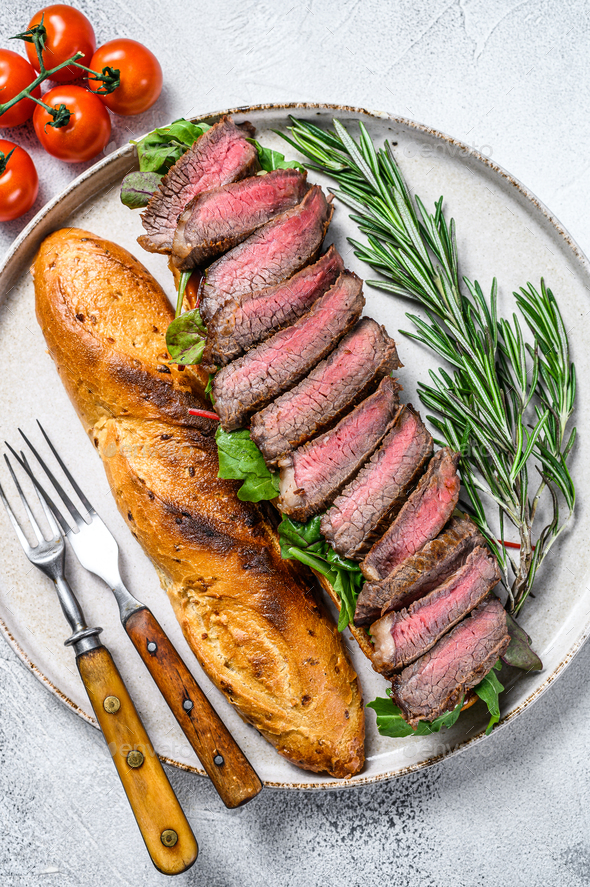 Grilled Homemade rib eye Steak sandwich with sliced roast beef, arugula