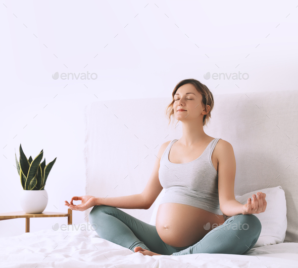 Pregnant woman in lotus pose doing meditation or breathing exercises for healthy pregnancy Stock