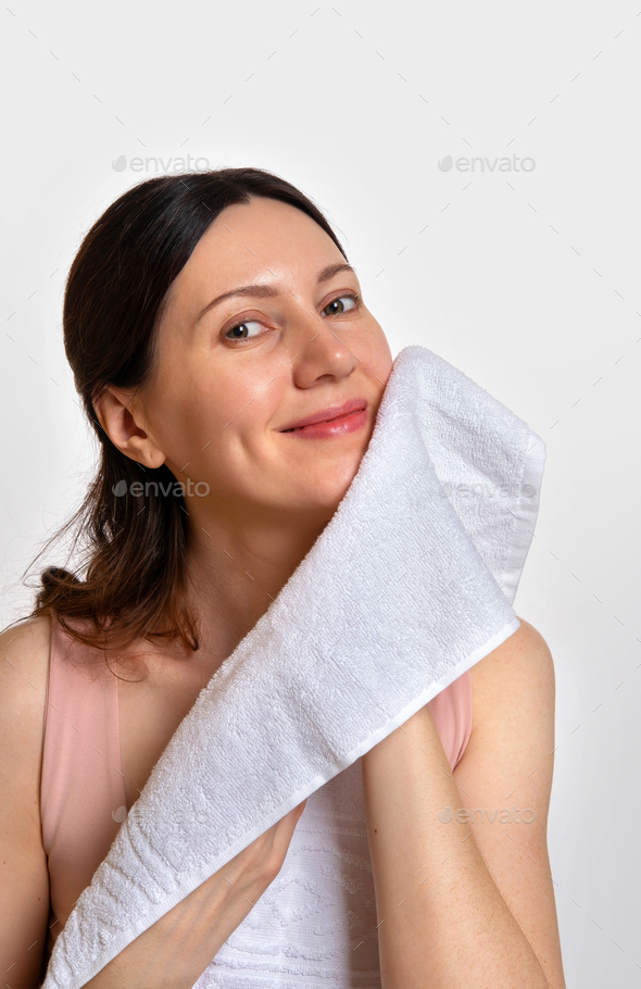 Washing face. Closeup of woman with towel. Beautiful woman wiping facial skin with soft facial