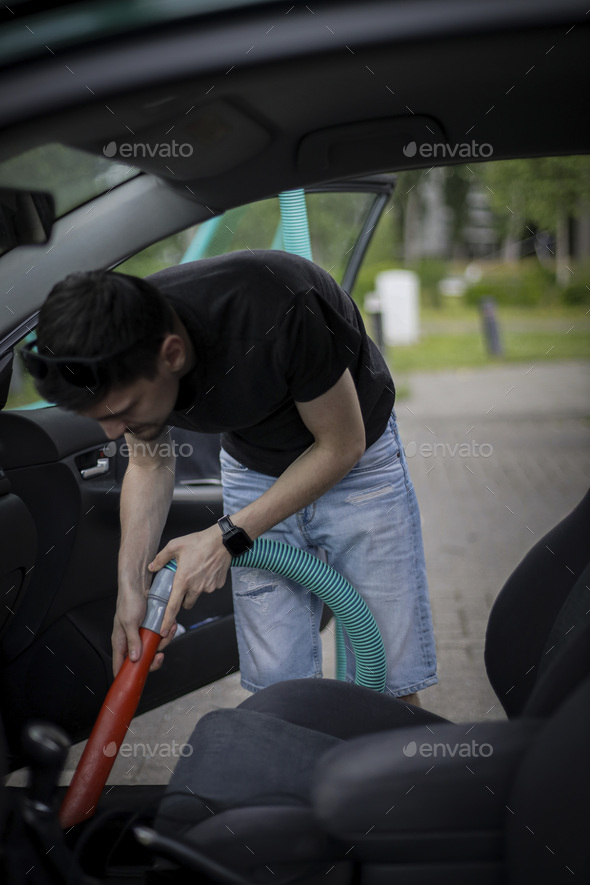 Caucasian man vacuuming a car at a gas station. Stock Photo by NataKor5
