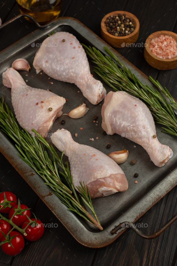 Raw chicken legs, spicy marinated drumsticks in cast iron sheet pan on