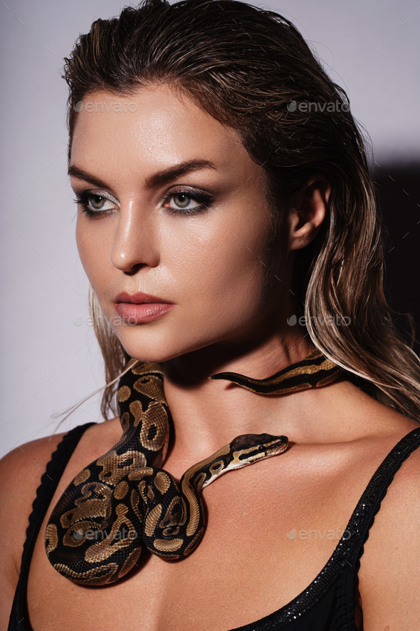 Stunning nude woman with python snake elegantly slithering over her
