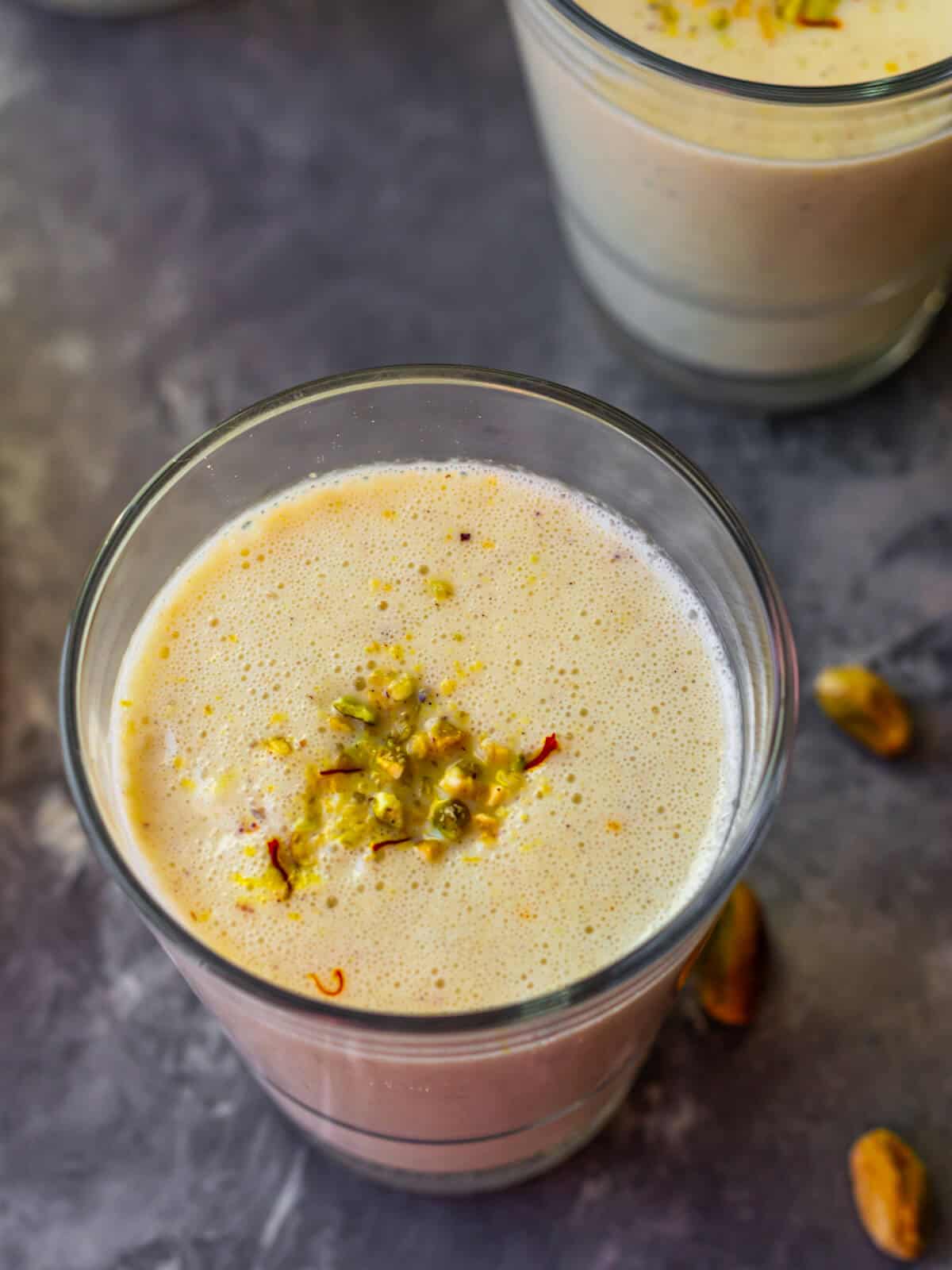 Saffron and Pistachio smoothie garnished with pistachio powder and saffron strands.