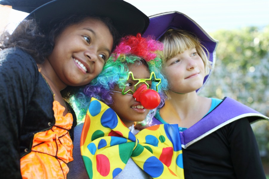This is a photo of some children dressed up for Halloween. One witch, one clown, and one wizard.